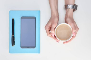 Mürekkep ile kaplı fincan sütlü kahve, mavi diery holding kadının eller 
