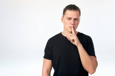 Genç çekici adam tutan indeks parmak yakın Bu dudaklar üzerinde bir WHI