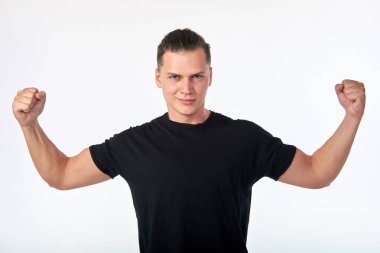 Ben güçlüyüm. Siyah gömlek giyen ve pazı gösteren yakışıklı genç gülümseyen kendine güvenen brunet portresi. Beyaz arka plan üzerine stüdyo fotooturumu. 