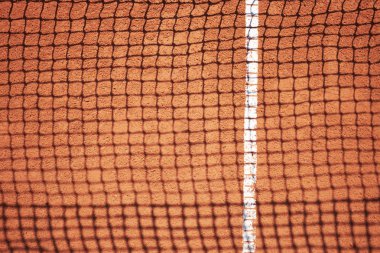 Kırmızı kum sahasında tenis ağın gölgesi 