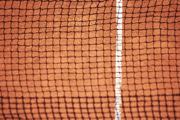 Kırmızı kum sahasında tenis ağın gölgesi 