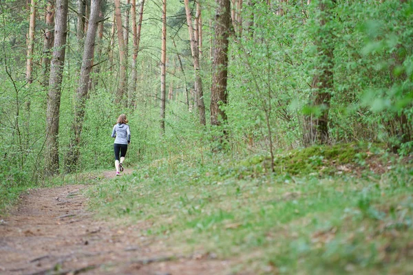 Atlética joven en zapatillas de deporte de color rosa corren en el bosque de primavera — Foto de Stock