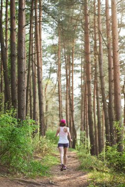 Pembe spor ayakkabılı atletik genç kadın bahar ormanında koşuyor