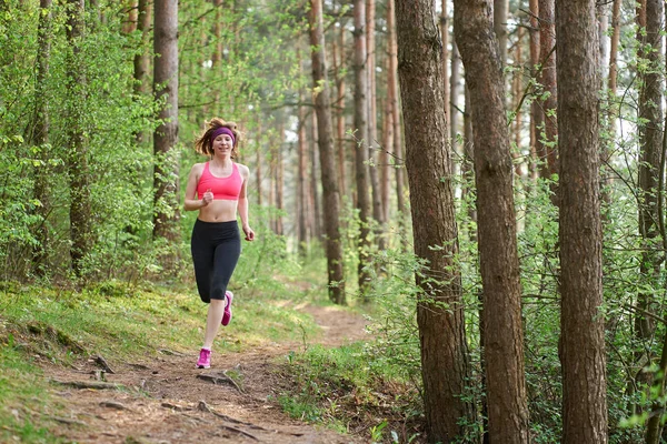 Atletische jonge vrouw in roze sneakers lopen in Spring forest — Stockfoto