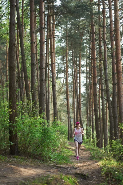 Atlética joven en zapatillas de deporte de color rosa corren en el bosque de primavera — Foto de Stock