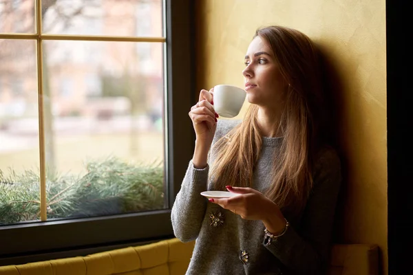 Genç çekici kız kafede çay ya da kahve içiyor.