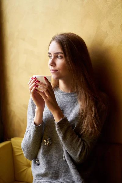 Молодая красивая девушка с длинными волосами пить кофе или чай в — стоковое фото