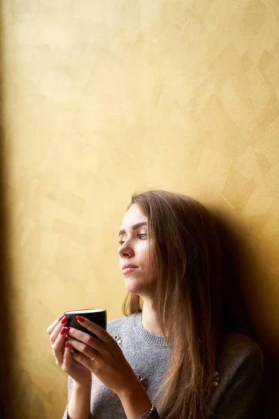 Молодая красивая девушка с длинными волосами пить кофе или чай в — стоковое фото