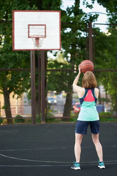 빨간 머리 마른 소녀 던지는 공 에 농구 후프 야외 — 스톡 사진