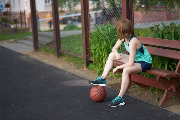 Redhead skinny caucasian girl with ball on the ground sitting an