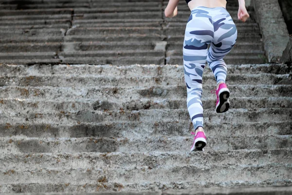 Woman in pink sneakers and trendy leggings running up the stairs — Stock Photo, Image