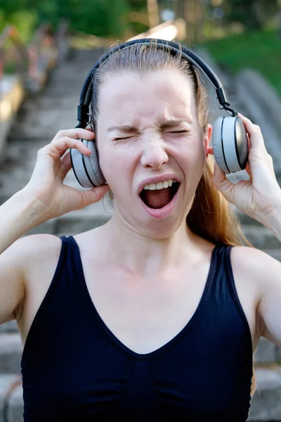 Young attractive sleepy woman listening to too loud music and ya