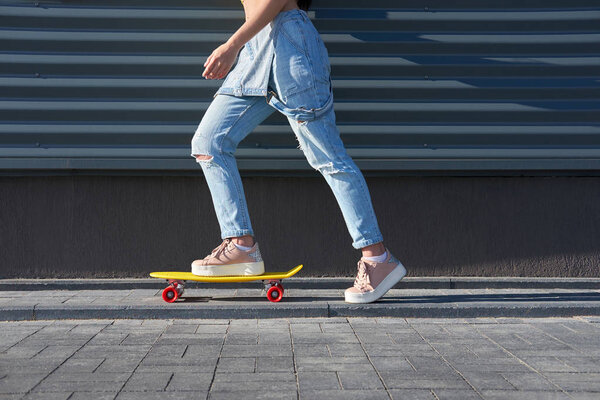 Girl wearing  blue denim overalls and trendy pink sneakers ridin