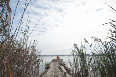 Eski iskele ve medita oturan parlak sarı ceket giyen kız
