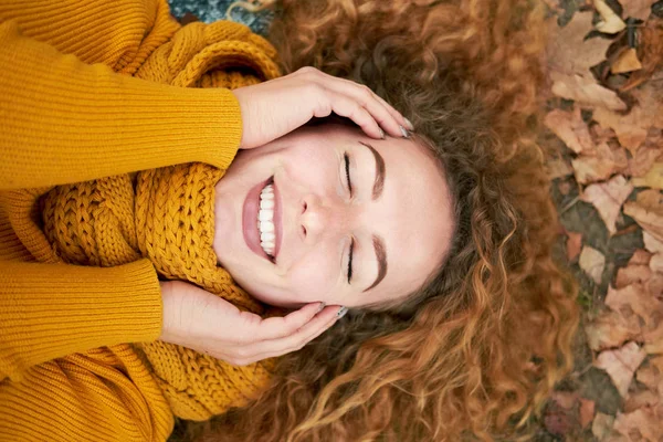 Rothaarige lockige fröhliche nettes Mädchen, das in den Herbstblättern liegt, ho — Stockfoto