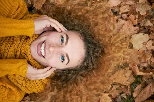 Rothaarige lockige fröhliche nettes Mädchen, das in den Herbstblättern liegt, ho — Stockfoto