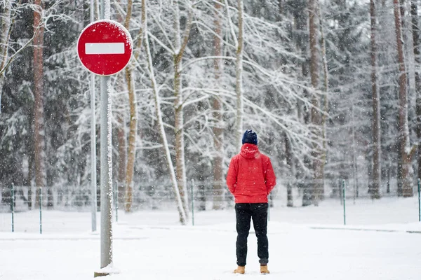 Ο άνθρωπος φοράει κόκκινο μπουφάν χειμώνα στέκεται κοντά σε καμία πινακίδα entrans δρόμο — Φωτογραφία Αρχείου