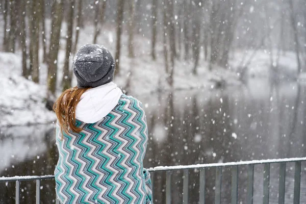 Menina em chapéu cinza, coberto de padrões azuis xadrez apreciando snowfa — Fotografia de Stock