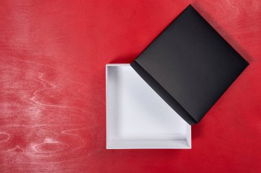 Kırmızı ahşap arka planda siyah hediye kutusunu aç. Düz Yatay.