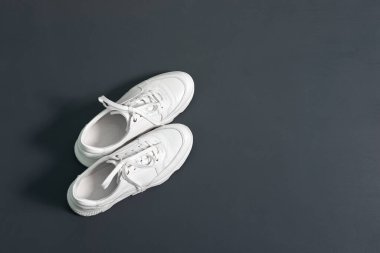 Fotokopi odası olan gri duvar arkasında beyaz kadın deri ayakkabıları var. Kalın tabanlı ayakkabılar..