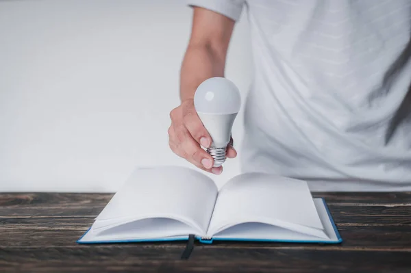 Man Håller Glödlampa Handen Och Sätter Den Bok Lärande Koncept — Stockfoto