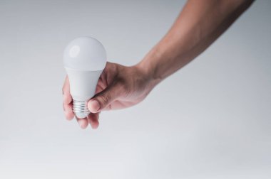 LED lamba elinde. Beyaz arka plandaki masa alanı..