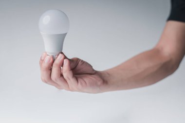 LED lamba elinde. Beyaz arka plandaki masa alanı..