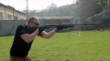 Gözlüklü adam hedefleyen ve av tüfeği ile ateş eder. 50 fps