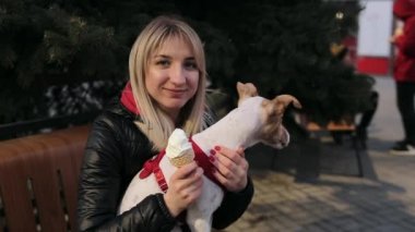 Ağır çekim. Neşeli kız köpeğini bankta oturuyor ve poz dondurma ile. kadın köpek okşama