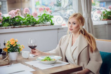 Bir açık hava restoranı kırmızı şarap içme sarışın genç kadın