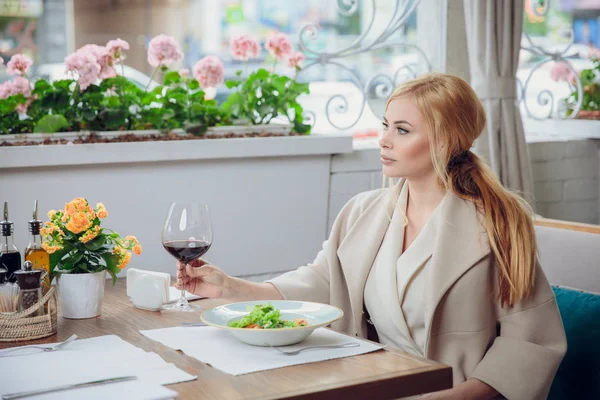 Bir açık hava restoranı kırmızı şarap içme sarışın genç kadın