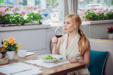sarışın kadın restautant öğle yemeği. Güzel bir kadın içki kırmızı şarap ve birini bekliyor