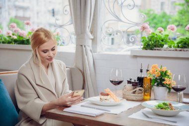 Akıllı telefon kullanan bir restoranda iş kadın. Bir muhatap için bekleyen güzel bir kadın. Beklenti