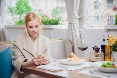 Akıllı telefon kullanan bir restoranda iş kadın. Bir muhatap için bekleyen güzel bir kadın. Beklenti