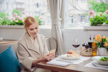 bir akşam yemeği ve cep telefonları kullanarak şehrin caddeleri üzerinde sarı saçlı Genç modeli. kadın birilerini bekliyor