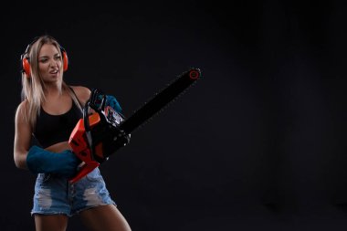 İnşaat işçisi çalışan chainsawattractive kadın ile poz çekici genç bir kadın. Bir kadın inşaat işçisi portresi. Bina, kavram onarın. Feminizm ve cinsiyet eşitliği. Boşaltmak