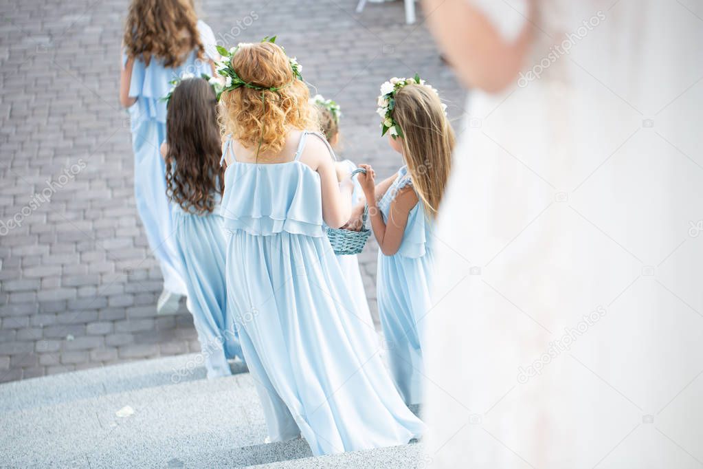 Little bridesmaids in flower wreathes walk along the path to wedding altar. wedding ceremony