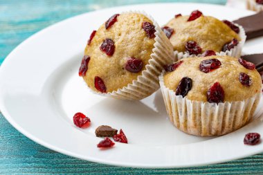 Vanilyalı kek beyaz plaka ve mavi ahşap rustik masa üzerinde kurutulmuş kiraz ile. Çikolata