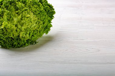 Beyaz ahşap zemin üzerine yeşil batavia marul salatası. Kopya alanı