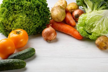 Beyaz ahşap zemin üzerinde çeşitli ham organik sebze ile kompozisyon