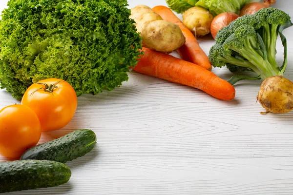 Beyaz ahşap zemin üzerinde çeşitli ham organik sebze ile kompozisyon