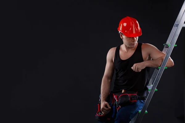 Trabajador Apoya Una Escalera Mira Hacia Arriba Sobre Fondo Negro — Foto de Stock