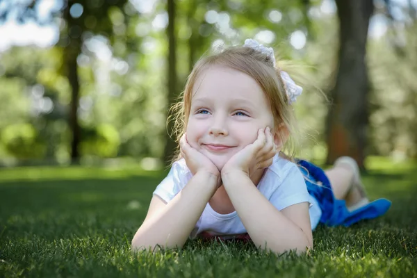 Kız bir yaz parkta çim halı üzerinde yatıyor.