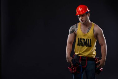 Ağır sanayi ve iş kavramı - emin yüz ifadesi olan adam. Kas seksi profesyonel Oluşturucusu, koruyucu kask tamirci. Acımasız adam dövme siyah bir zemin üzerine