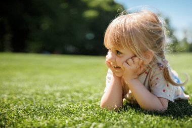 Mutlu küçük kız parkta eğleniyor. küçük kız çimlere yatıyor. Kopya alanı