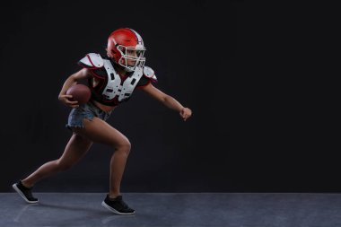 Ragbi topu ile çalışan ve agresif çığlık siyah arka plan cinsel sportif kadın. Uzay kopyalayın. cinsiyet eşitliği