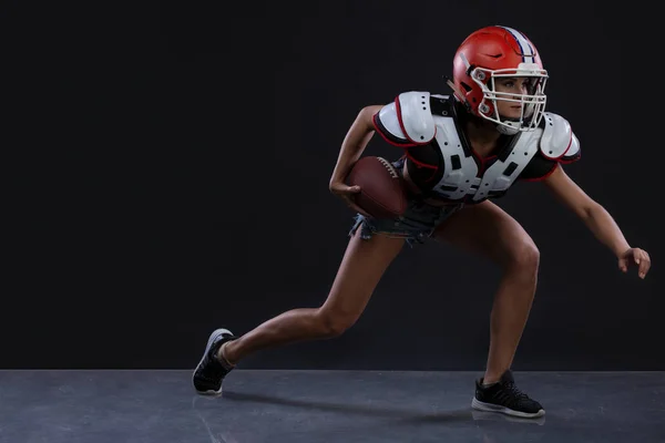 Sexual sportive woman running with rugby ball and screaming aggressively at black background. Copy space. gender equality