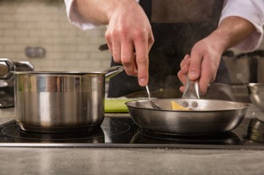 Lokanta mutfağı soba pan ile Şef. Eller yemek ilave edin.