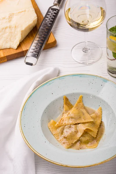 İtalyan Mantı makarna parçası Parmesan ve beyaz şarap ile plaka üzerinde. dikey fotoğraf