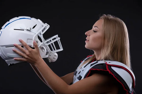 Attractive female american football player in uniform posing with helmet. girl sportswoman. Gender equality